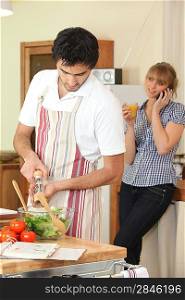 Husband cooking whilst wife telephones