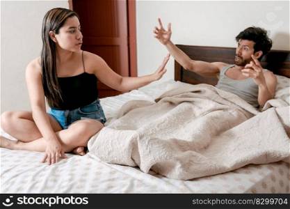 Husband fighting with his wife in bed. Upset wife with husband in bedroom bed, Young couple arguing in bed room. Concept of couple problems in bed