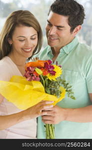 Husband giving wife flowers and smiling