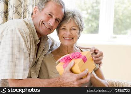 Husband giving wife gift in living room smiling