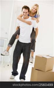 Husband giving wife piggyback in new home smiling