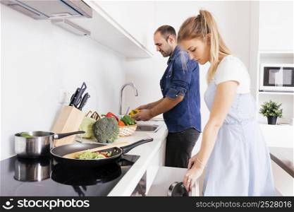 husband helping her blonde young wife preparing food kitchen