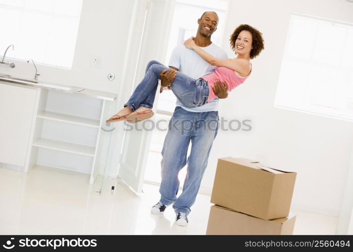 Husband holding wife in new home smiling