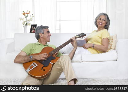 Husband playing the guitar while wife is listening