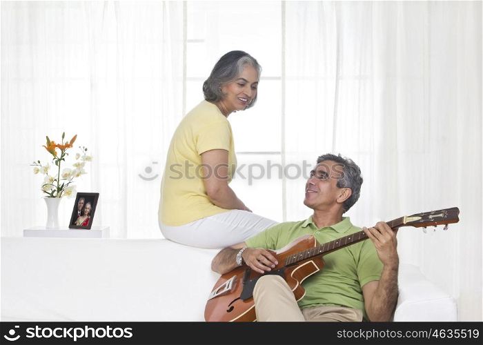 Husband playing the guitar while wife is listening