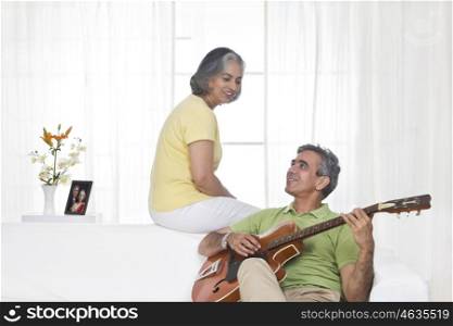 Husband playing the guitar while wife is listening