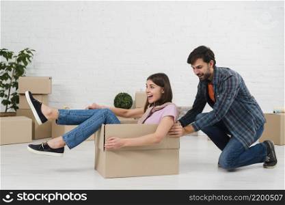 husband pushing his wife sitting cardboard box