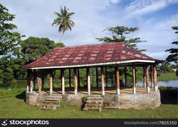 Hut with rusty iron roof on the grass near lake in Upolu, Samoa