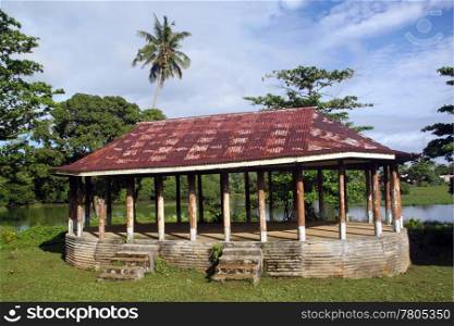 Hut with rusty iron roof on the grass near lake in Upolu, Samoa