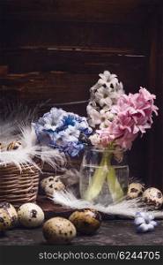 Hyacinths flowers bunch and quail eggs with feathers on rustic wooden background, side view. Easter greeting card