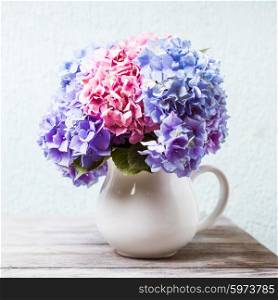 Hydrangea flowers in a white jug on the shabby wooden table. Hydrangea bouquet