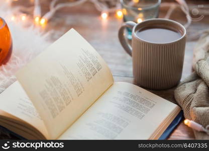 hygge and cozy home concept - book and cup of coffee or hot chocolate on table. book and cup of coffee or hot chocolate on table