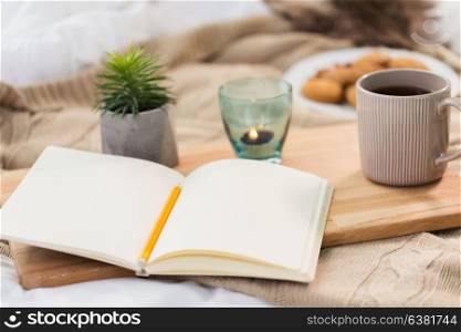 hygge and inspiration concept - diary, tea and candle in holder at home. diary, tea and candle in holder at home