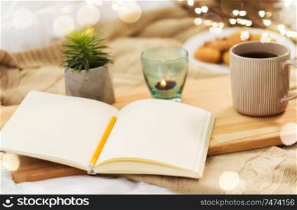 hygge and inspiration concept - diary, tea and candle in holder at home. diary, tea and candle in holder at home