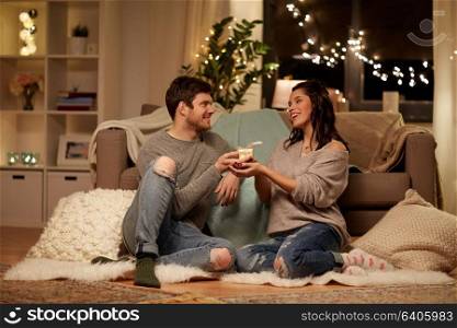 hygge, holidays and people concept - happy couple with gift box at home. happy couple with gift box at home