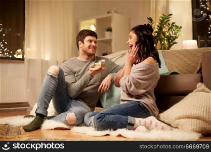 hygge, holidays and people concept - happy couple with gift box at home. happy couple with gift box at home. happy couple with gift box at home