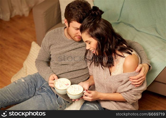 hygge, leisure and people concept - happy couple drinking cacao with marshmallow and hugging at home. happy couple drinking cacao at home. happy couple drinking cacao at home