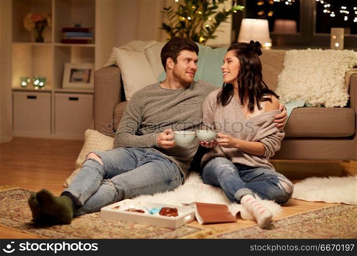 hygge, leisure and people concept - happy couple drinking cacao with marshmallow at home. happy couple drinking cacao at home. happy couple drinking cacao at home