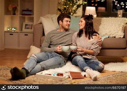 hygge, leisure and people concept - happy couple drinking cacao with marshmallow at home. happy couple drinking cacao at home. happy couple drinking cacao at home