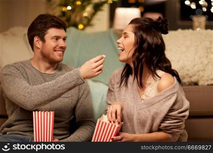 hygge, leisure and people concept - happy couple eating popcorn at home. happy couple eating popcorn at home. happy couple eating popcorn at home