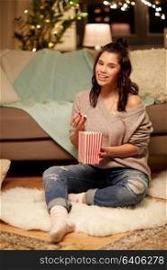 hygge, leisure and people concept - happy woman eating popcorn at home. happy woman eating popcorn at home