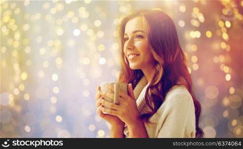 hygge, leisure, christmas and people concept - happy young woman with cup of coffee or tea at home. happy woman with cup of tea or coffee at home