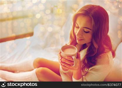 hygge, leisure, christmas and people concept - happy young woman with cup of coffee or cocoa in bed at home. happy woman with cup of cocoa in bed at home