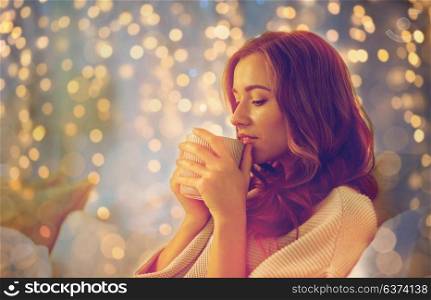 hygge, leisure, christmas and people concept - happy young woman with cup of coffee or tea in bed at home bedroom. happy woman with cup of coffee in bed at home