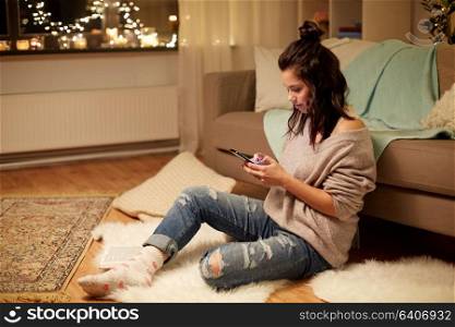hygge, technology and people concept - happy young woman with smartphone at home. happy young woman with smartphone at home