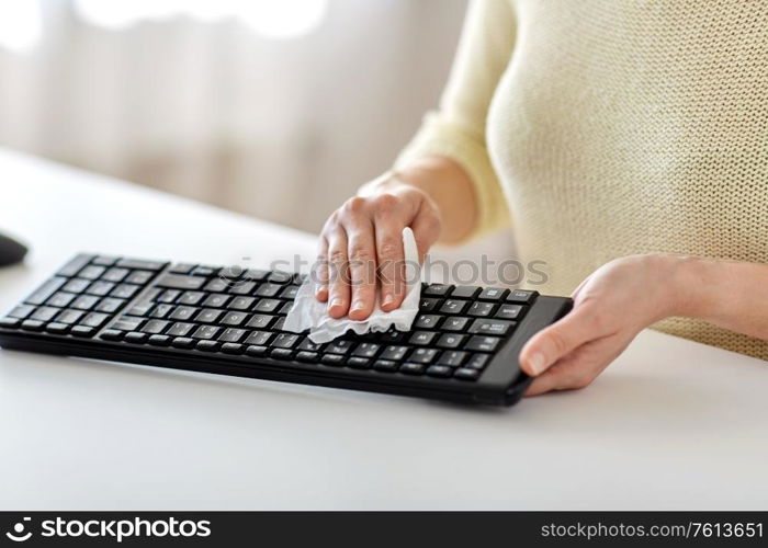 hygiene and disinfection concept - close up of woman cleaning computer keyboard with paper tissue. close up of woman cleaning keyboard with tissue