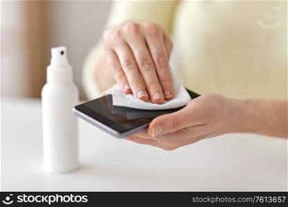 hygiene and disinfection concept - close up of woman hands cleaning smartphone with hand sanitizer and tissue. close up of woman cleaning smartphone