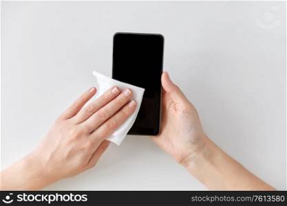 hygiene and disinfection concept - close up of woman hands cleaning smartphone with tissue. close up of hands cleaning smartphone with tissue
