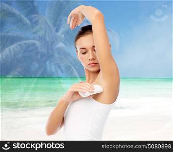 hygiene, bodycare and people concept - beautiful young woman applying antiperspirant or stick deodorant over exotic beach background with double exposure effect. woman with antiperspirant deodorant over beach