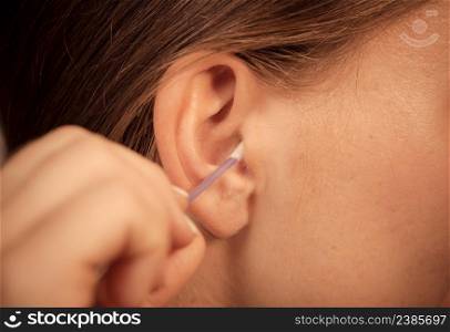 Hygiene concept. Woman cleaning ear with cotton swabs closeup . Woman cleaning ear with cotton swabs closeup