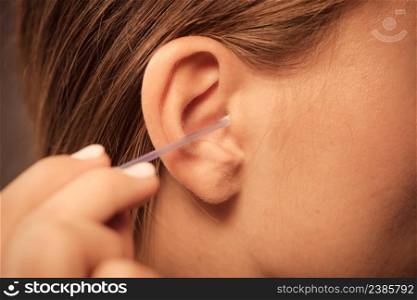 Hygiene concept. Woman cleaning ear with cotton swabs closeup . Woman cleaning ear with cotton swabs closeup