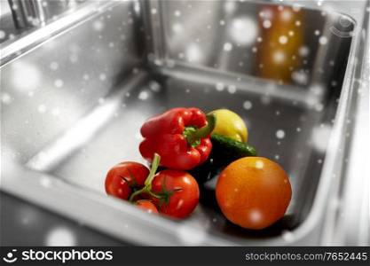 hygiene, food and safety concept - fruits and vegetables in stainless steel kitchen sink in winter over snow. fruits and vegetables in kitchen sink