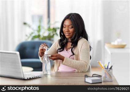 hygiene, health care and safety concept - african american woman using antibacterial hand sanitizer at home office. woman using hand sanitizer at home office