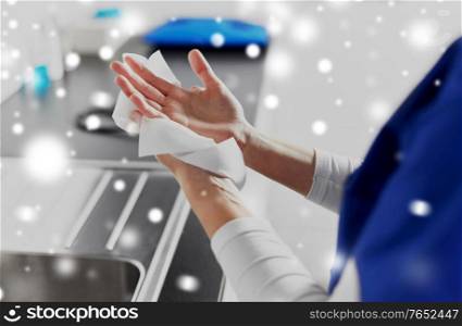 hygiene, health care and safety concept - close up of female doctor or nurse drying hands with paper tissue at hospital in winter over snow. doctor or nurse drying hands with paper tissue