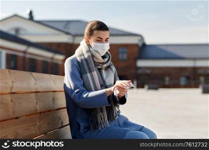 hygiene, health care and safety concept - close up of woman in protective face mask cleaning hands with antiseptic wet wipe on city street. woman in mask cleaning hands with antiseptic wipe