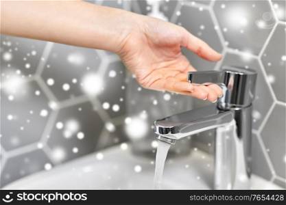 hygiene, health care and safety concept - close up of woman&rsquo;s hand opening water tap in winter over snow. close up of woman&rsquo;s hand opening water tap
