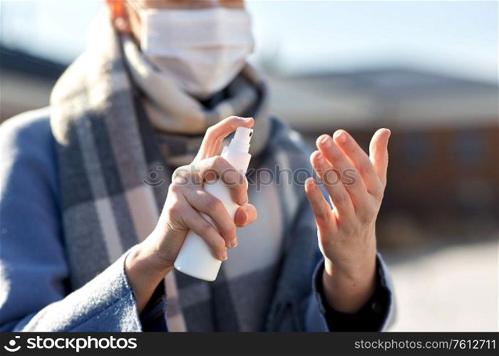 hygiene, health care and safety concept - close up of woman spraying antibacterial hand sanitizer outdoors. close up of woman spraying hand sanitizer