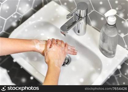 hygiene, health care and safety concept - close up of woman washing hands with liquid soap in winter over snow. close up of woman washing hands with liquid soap