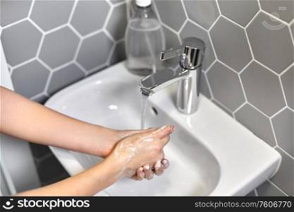 hygiene, health care and safety concept - close up of woman washing hands with liquid soap. close up of woman washing hands with liquid soap