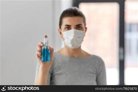 hygiene, health care and safety concept - close up of woman wearing protective medical mask holding antibacterial hand sanitizer. close up of woman in mask holding hand sanitizer