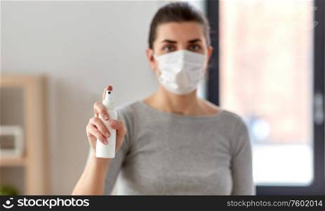 hygiene, health care and safety concept - close up of woman wearing protective medical mask holding antibacterial hand sanitizer. close up of woman in mask holding hand sanitizer