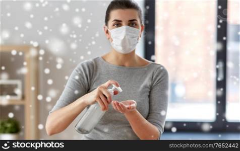 hygiene, health care and safety concept - close up of woman wearing protective medical mask applying antibacterial hand sanitizer in winter over snow. close up of woman in mask applying hand sanitizer
