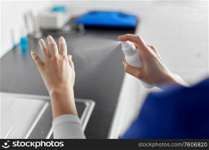 hygiene, healthcare and safety concept - close up of female doctor or nurse spraying antibacterial hand sanitizer at hospital. doctor or nurse spraying hand sanitizer