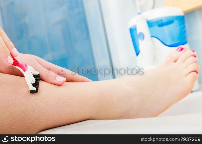 Hygiene skin body care concept. Hair removal. Closeup woman shaving legs with razor blade in bathroom