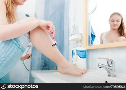 Hygiene skin body care concept. Hair removal. Closeup woman shaving legs with razor blade in bathroom