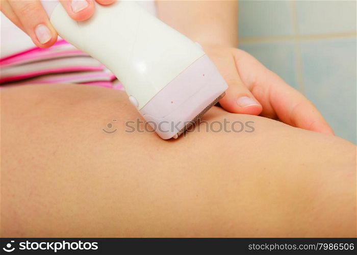 Hygiene skin body care concept. Hair removal. Closeup woman shaving legs with electric shaver depilator in bathroom